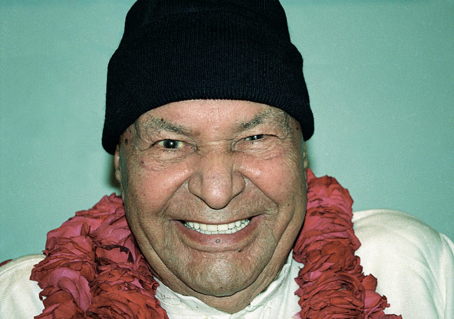laughing Papaji with black hat and red Mala around his neck