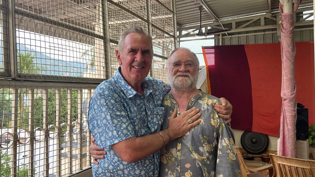 John David in a warm embrace with a friend on the terrace